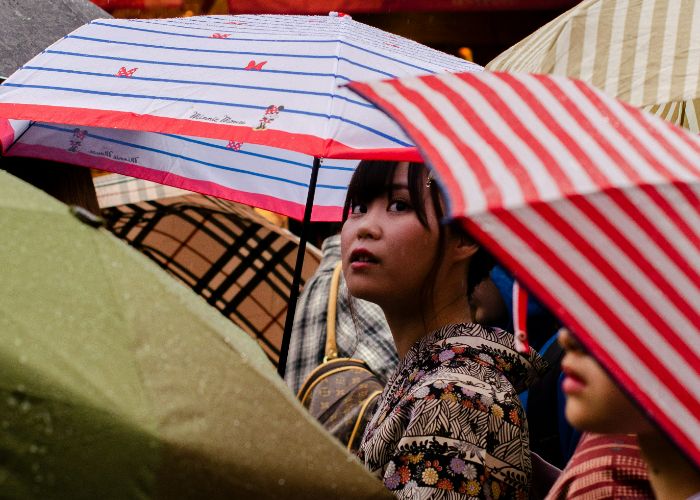 A woman peeking out from under an umbrella on a rainy day in Japan.